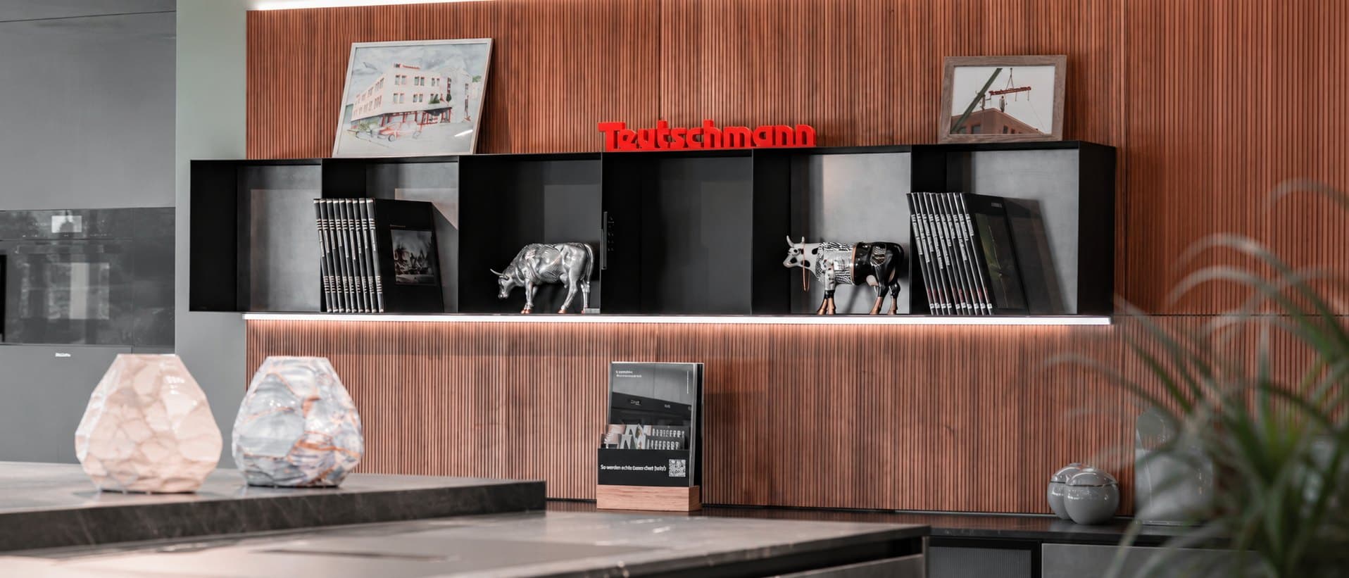 Le mur signature du showroom Teutschmann : enseigne, revues et vaches en porcelaine